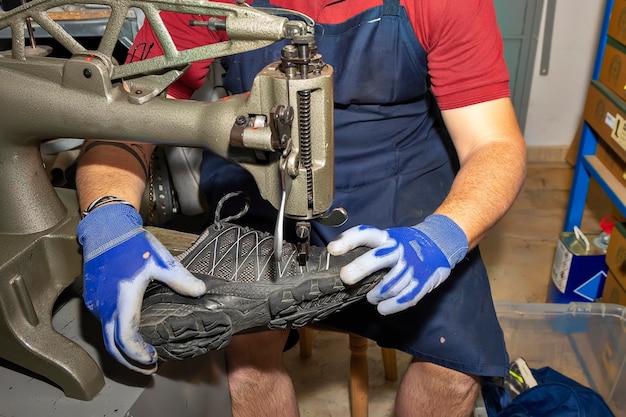 Jeune cordonnier réparant des chaussures dans un atelier de réparation.