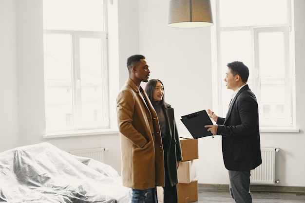 Photo jeune couple achetant une nouvelle maison. femme asiatique et homme africain. signature des documents à la nouvelle maison.