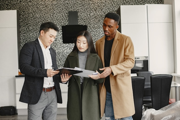 Jeune couple achetant une nouvelle maison. Femme asiatique et homme africain. Signature des documents à la nouvelle maison.