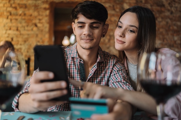 Jeune couple achetant ou payant par carte de crédit dans un restaurant.