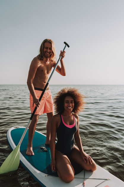 Jeune couple d&#39;adolescents en rangée surf en mer avec la pagaie.