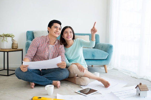 Jeune couple adulte asiatique séduisant planifiant un nouveau design de maison.