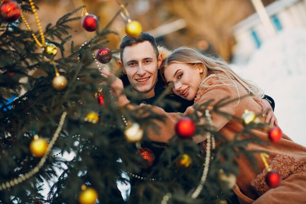 Jeune couple adulte décore le sapin de Noël dans la forêt d'hiver Concept de célébration de fête de vacances de pin du nouvel an