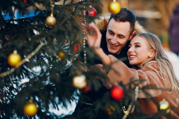 Jeune couple adulte décore le sapin de Noël dans la forêt d'hiver Concept de célébration de fête de vacances de pin du nouvel an