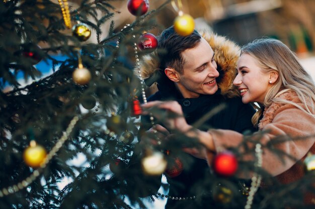 Jeune couple adulte décore le sapin de Noël dans la forêt d'hiver Concept de célébration de fête de vacances de pin du nouvel an