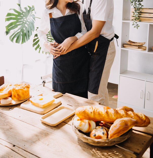 Un jeune couple d'adultes heureux préparent le petit déjeuner et boivent du café ensemble dans la cuisine confortable de la maison le matin à la maison préparent le repas et sourient style de vie, loisirs et concept d'amour