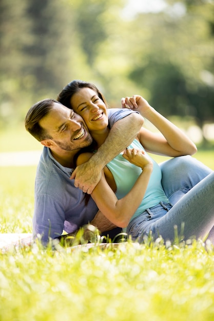 Jeune couple affectueux assis sur l'herbe verte du parc