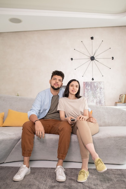 Jeune couple affectueux regardant un film à la télévision dans le salon