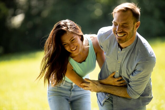 Jeune couple affectueux s'amusant sur l'herbe verte du parc