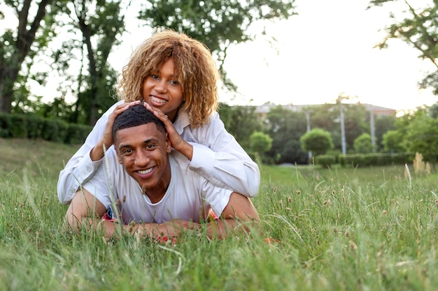 Un jeune couple afro-américain amoureux se trouve ensemble sur l'herbe dans le parc