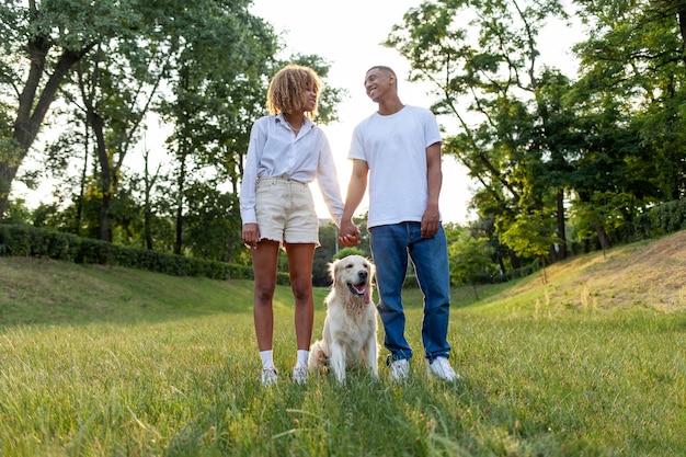 Jeune couple afro-américain se tient avec un chien et se tient la main dans le parc