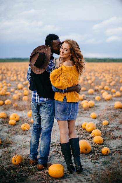 Un jeune couple d'agriculteurs debout dans un champ de citrouilles