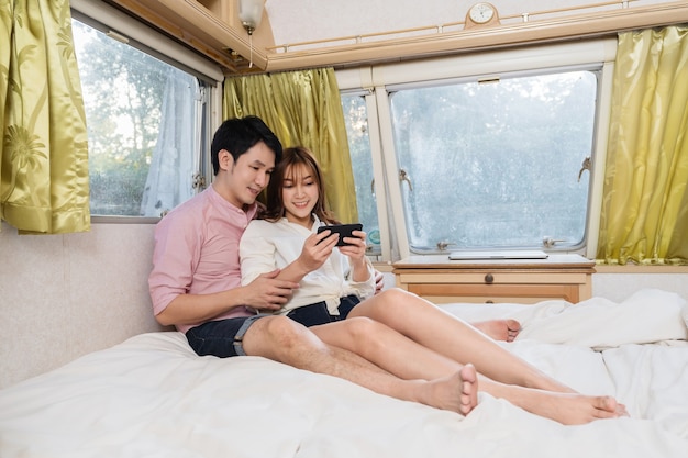 Jeune couple à l'aide de smartphone sur le lit d'un camping-car RV van camping-car