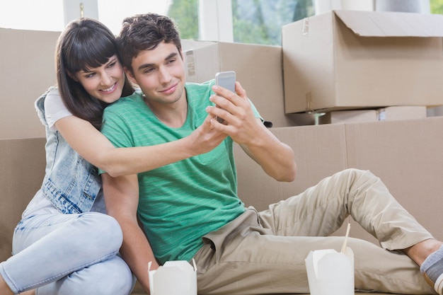 Jeune couple à l'aide d'un téléphone portable dans leur nouvelle maison