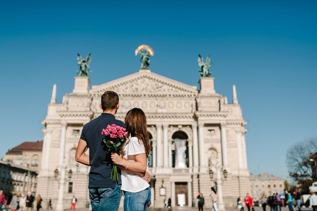 Jeune couple aimant avec un bouquet de fleurs debout en arrière et regardant la ville