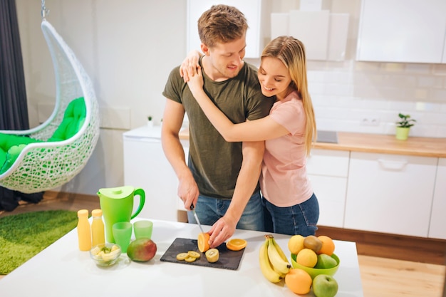 Jeune couple aimant la cuisson des fruits sucrés biologiques pour le jus au tableau blanc