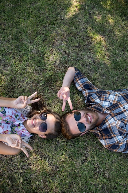 Jeune couple allongé sur l&#39;herbe, souriant à la caméra