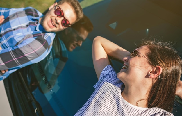 Photo jeune couple allongé sur le pare-brise