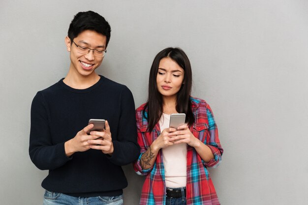 Jeune couple d'amoureux asiatique à l'aide de téléphones mobiles.