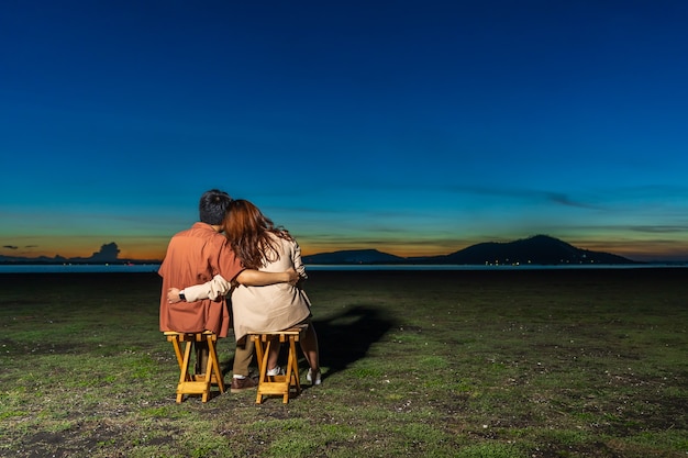 Jeune couple amoureux assis et étreignant l'herbe déposée la nuit