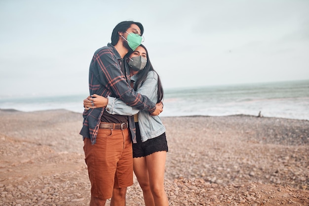 Jeune couple amoureux assis sur la plage pendant un beau coucher de soleil