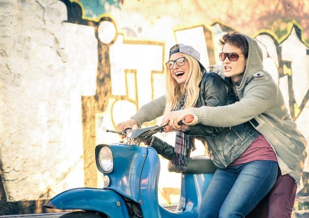 Jeune couple d'amoureux ayant du plaisir sur un cyclomoteur vintage