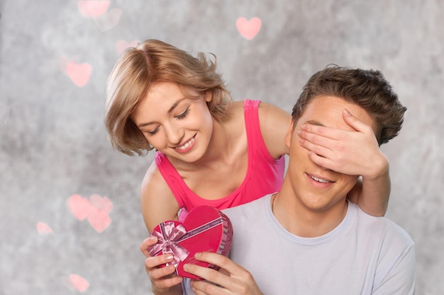 Jeune couple amoureux célébrant la Saint-Valentin en donnant un cadeau surprise.