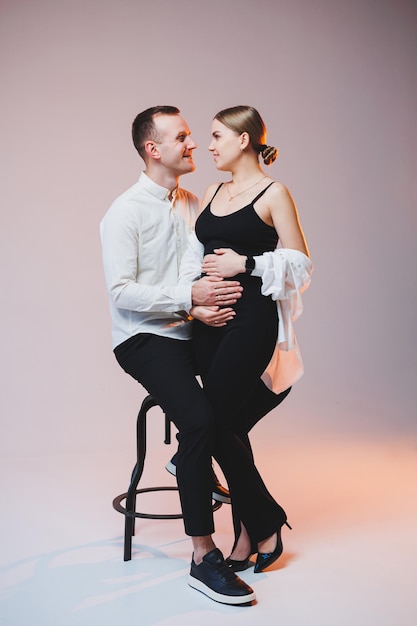 Jeune couple amoureux en chemises blanches étreignant sur fond blanc Un couple marié heureux se regarde amoureusement dans les yeux Le concept de relations familiales saines