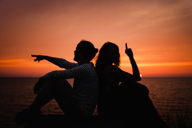 Jeune couple amoureux contre le coucher du soleil en mer