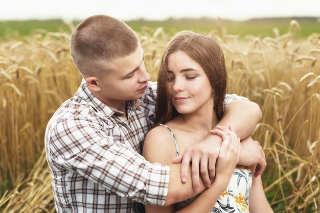 Jeune couple amoureux dans un champ de blé homme et fille étreignant dans la nature