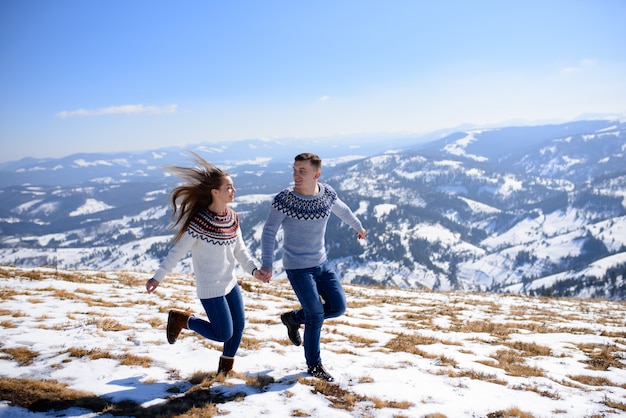 Jeune couple d'amoureux à une date au sommet d'une montagne enneigée