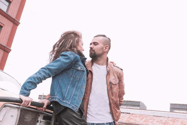 Jeune couple amoureux debout près de la voiture dans le parking de la ville