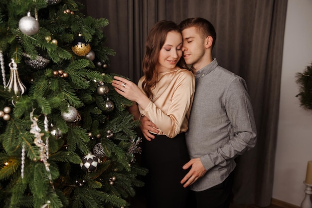 Jeune couple amoureux décorant ensemble le sapin de Noël