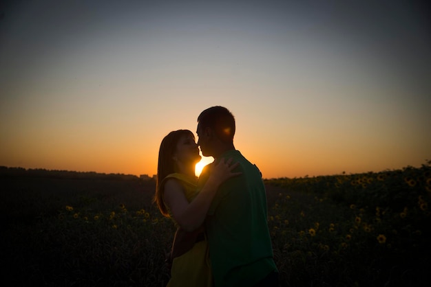 Un jeune couple amoureux sur fond de coucher de soleil dans un champ