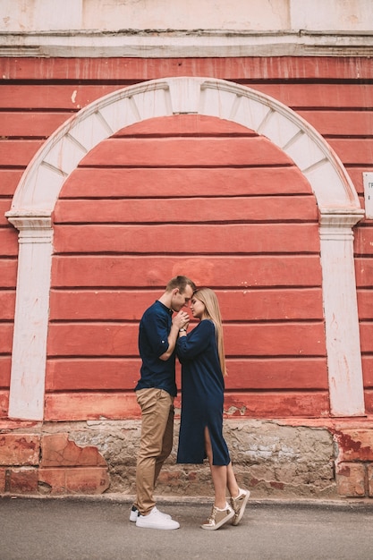 Jeune couple amoureux sur le fond d'un mur rouge. Heureux couple marié lors d'une promenade dans la ville