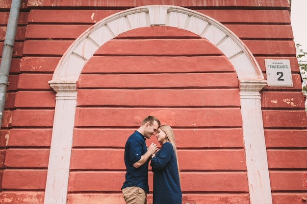 Jeune couple amoureux sur le fond d'un mur rouge. Heureux couple marié lors d'une promenade dans la ville