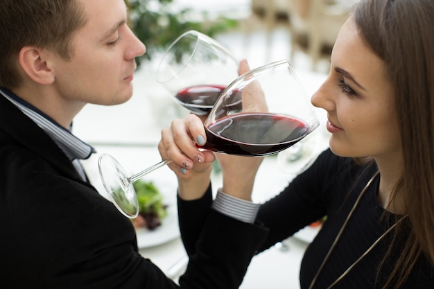 Jeune couple amoureux heureux célébrant avec du vin rouge au restaurant. fraternité