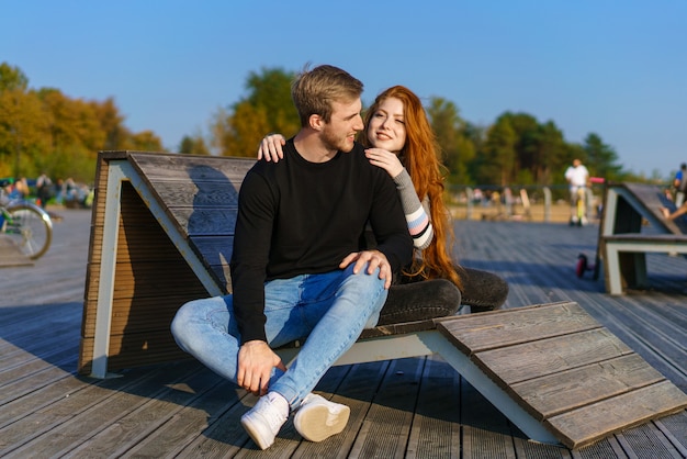 Un jeune couple amoureux un homme et une femme embrassent sur un banc dans l'aire de loisirs une belle redha...