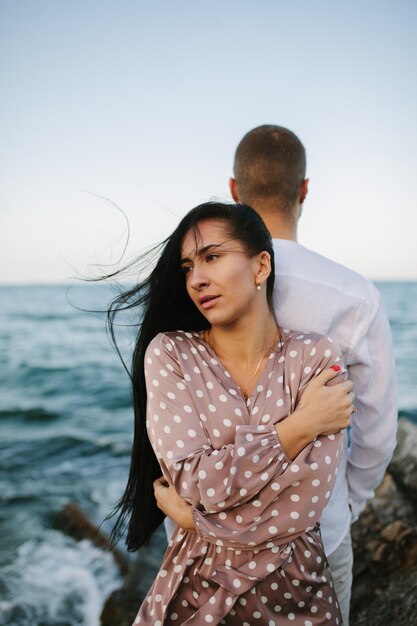 Jeune couple amoureux Un homme et une femme séduisants profitant d'une soirée romantique sur la plage en regardant le coucher du soleil