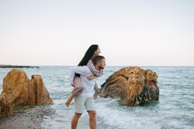 Jeune couple amoureux Un homme et une femme séduisants profitant d'une soirée romantique sur la plage en regardant le coucher du soleil