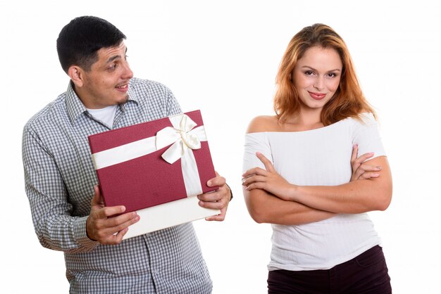 Jeune couple amoureux de l'homme regardant la femme lors de l'ouverture de la boîte-cadeau à la surprise