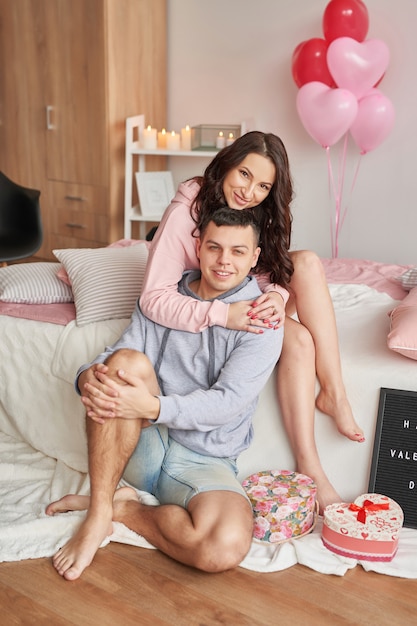 Jeune couple amoureux à la maison sur le lit pour célébrer la Saint Valentin