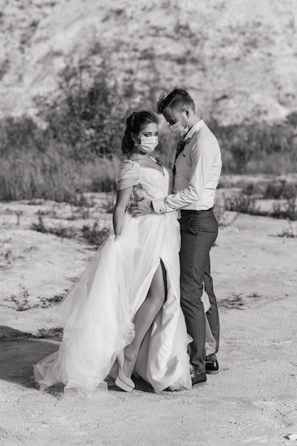 Jeune couple amoureux marchant dans des masques médicaux dans le parc pendant la quarantaine le jour de leur mariage.