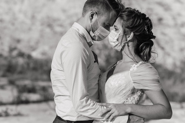 Jeune couple amoureux marchant dans des masques médicaux dans le parc pendant la quarantaine le jour de leur mariage.