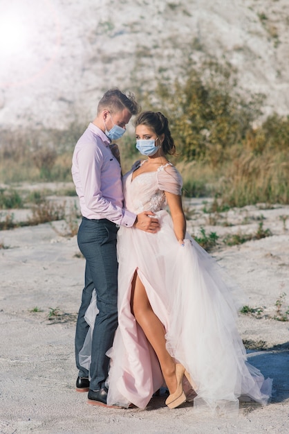 Jeune couple amoureux marchant dans des masques médicaux dans le parc pendant la quarantaine