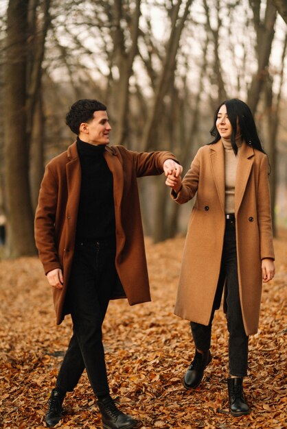 Jeune couple amoureux marchant dans le parc un jour d'automne