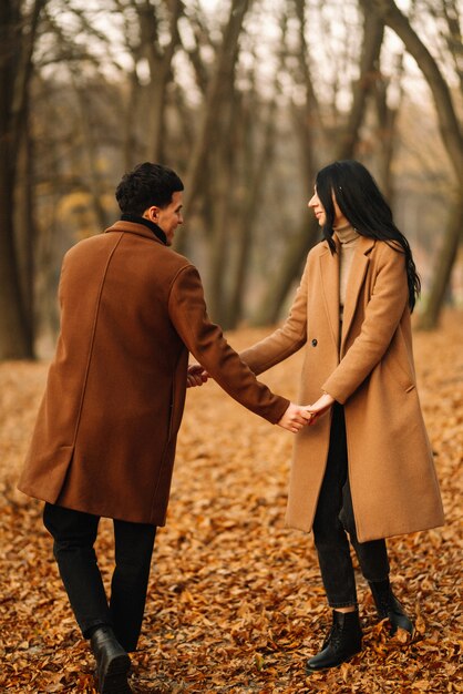 Jeune couple amoureux marchant dans le parc un jour d'automne