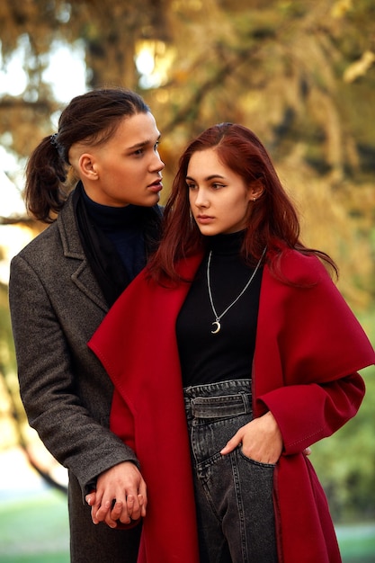 Jeune couple amoureux, marcher dans le parc en automne, tenant les mains regardant dans le coucher du soleil