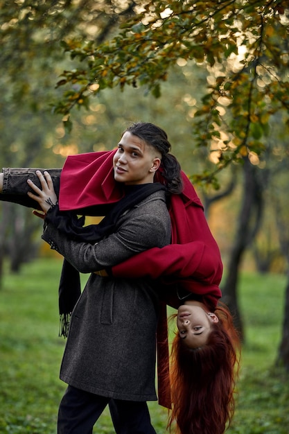 Jeune couple amoureux, marcher dans le parc en automne, tenant les mains regardant dans le coucher du soleil