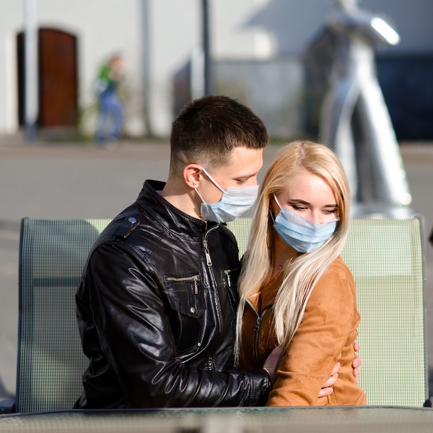 Jeune couple amoureux en masque médical de protection sur le visage en plein air dans la rue. Guy et fille dans la protection contre les virus.